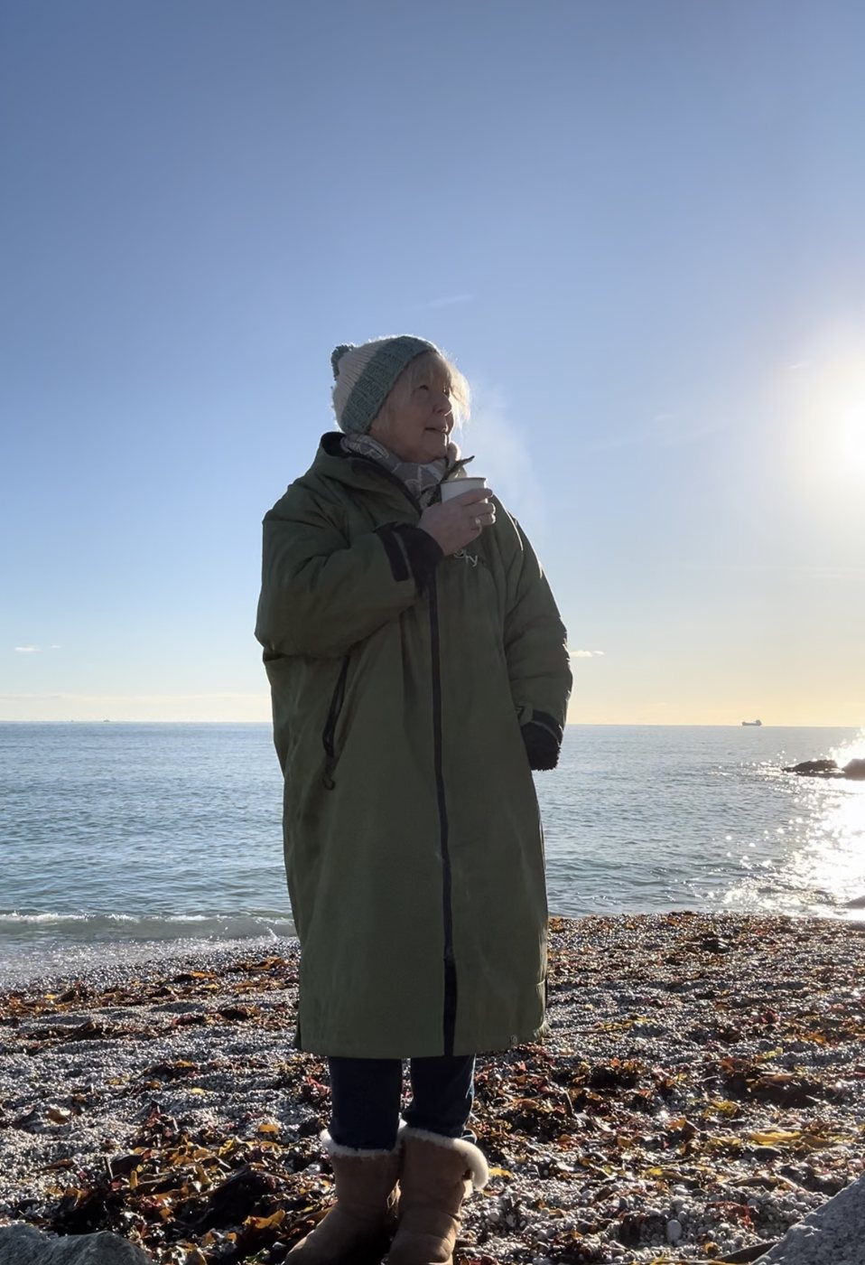 Ruth on the shore with a hot drink after a swim