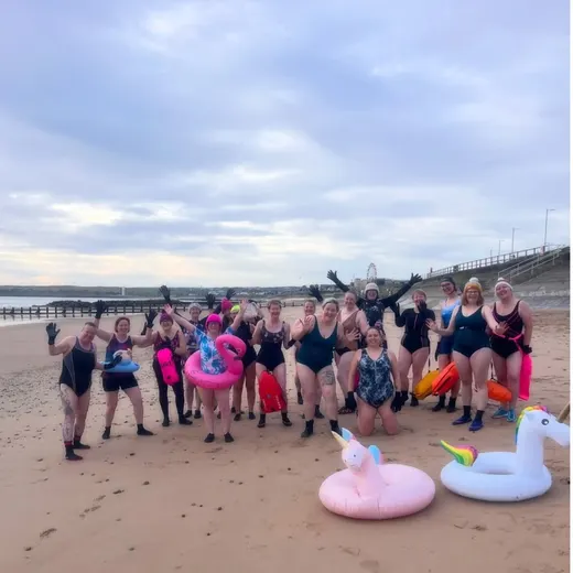 A group of flamingo-float swimmers on the beach