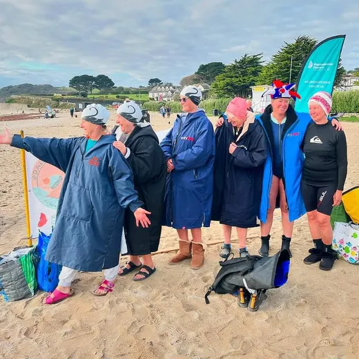 Swimmers in dryrobes on the beach holding a flag