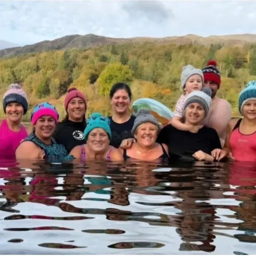 A row of swimmers in bobble hats in a lake