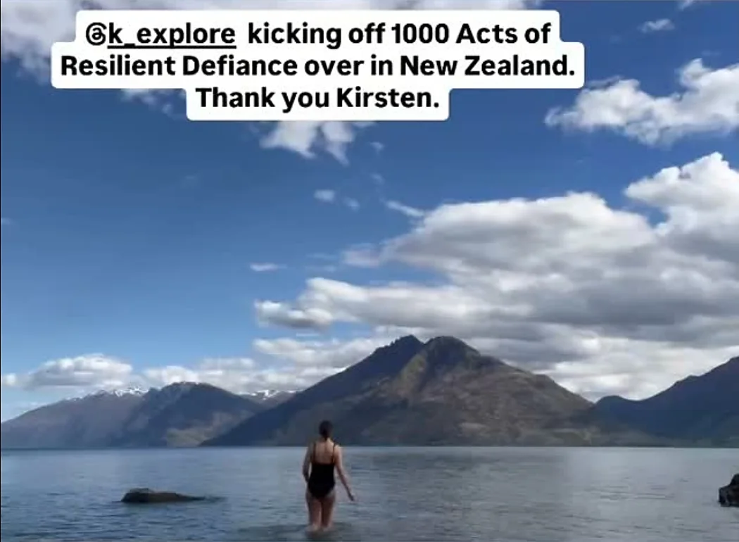 A swimmer walking into Lake Wakatipu with mountains behind