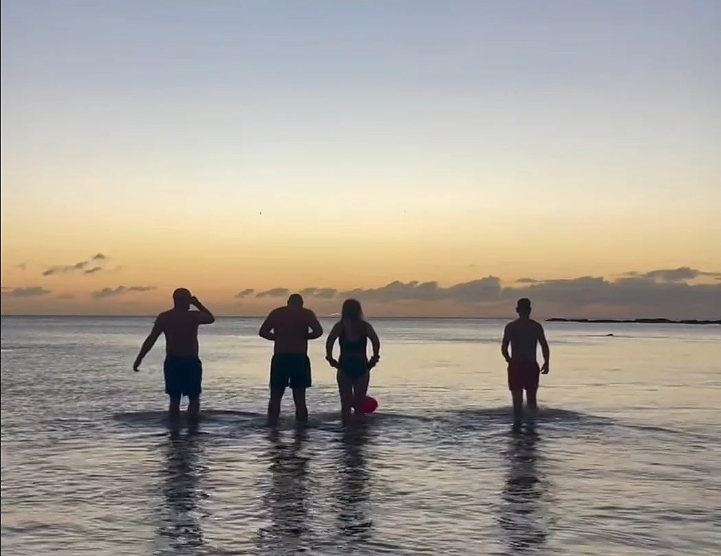 The Cullercoats Dippers wading into a calm sea at sunrise in Cullercoats Bay