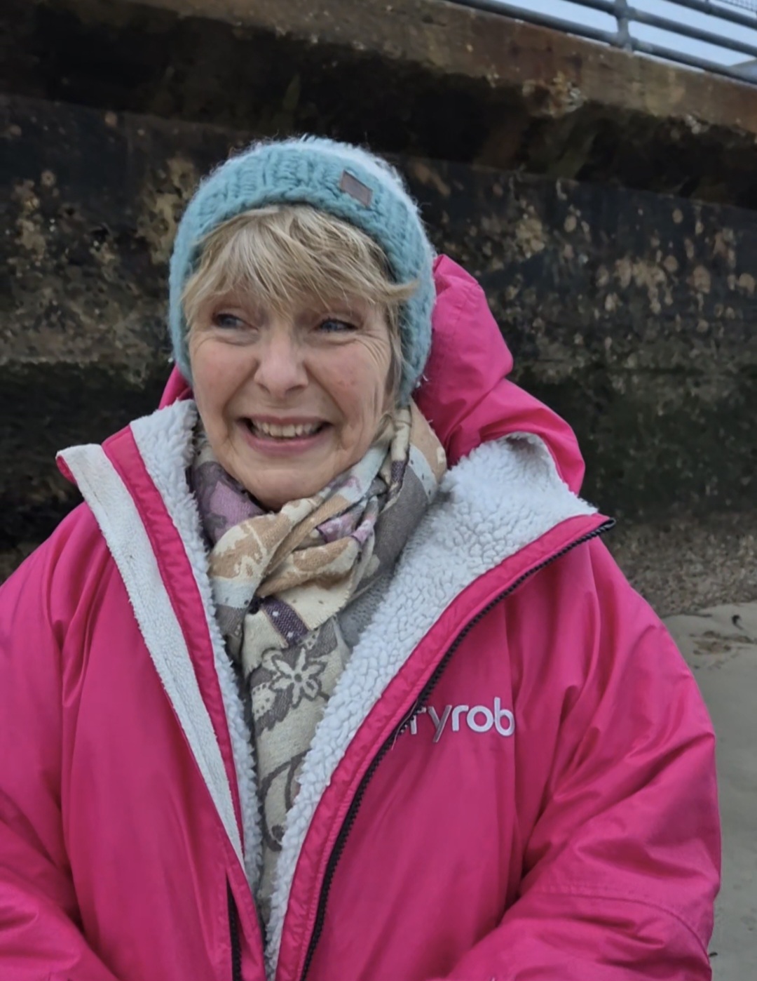 Ruth, mid-challenge, smiling on the shoreline